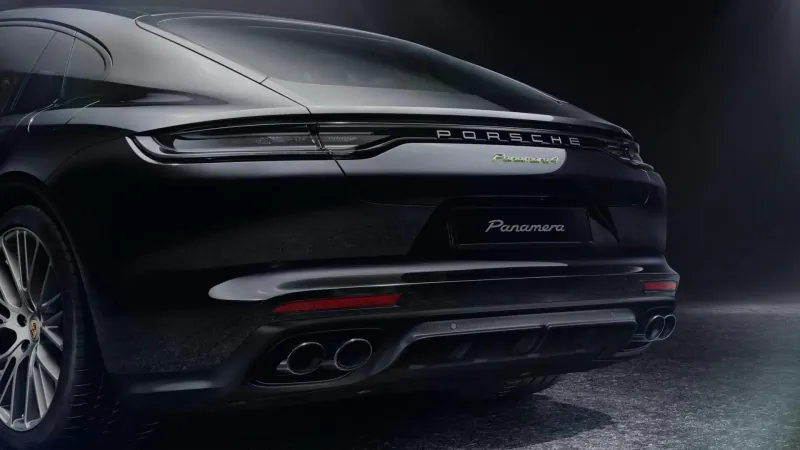 Rear view of black Porsche Panamera Platinum Edition with 'Panamera Platinum Edition' badge and quad exhausts in dark studio.