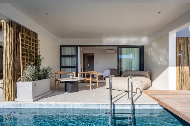 Spacious outdoor hotel suite at Abalone Hotel with lounge seating, plants, and private infinity pool overlooking sea.