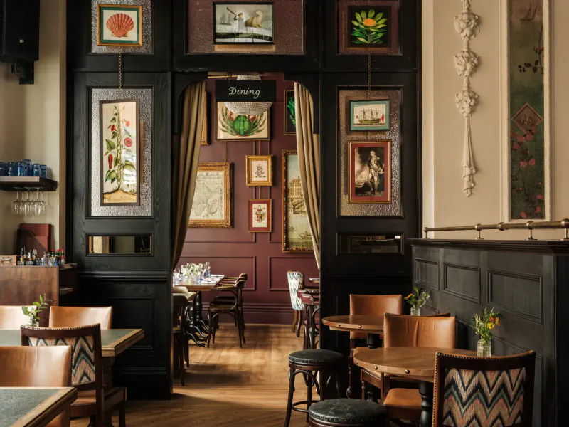 The Trafalgar Public House entrance on King’s Road, ornate wooden archway with botanical art, bar tables, and warm lighting. Now Open.