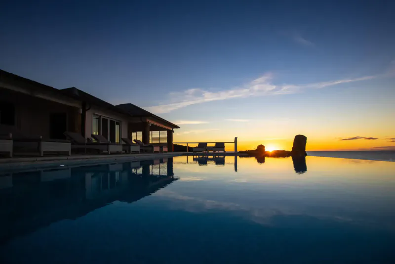 Luxury villa with infinity pool reflecting sunset over ocean at dusk, Antigua Sotheby's Realty.
