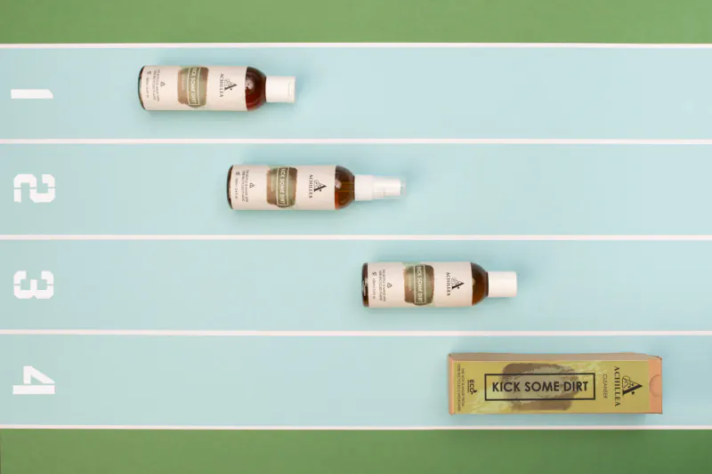 Four Kick Some Ass Achillea Beauty product bottles numbered 1-4 on a green track, with box at 4.