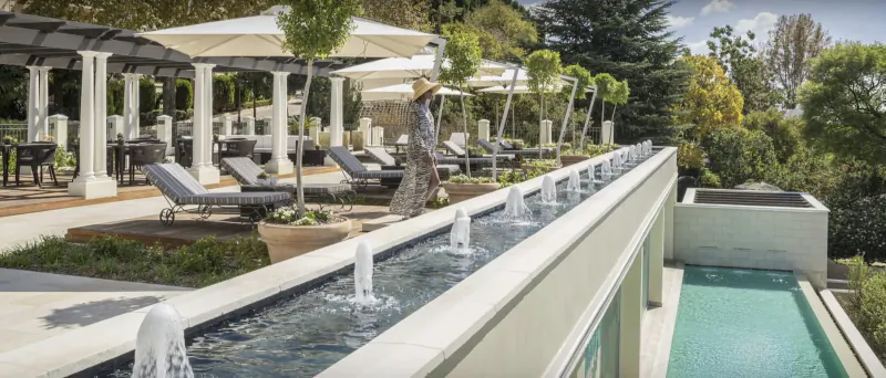 Four Seasons Westcliff pool deck above Johannesburg: lounge chairs under umbrellas, water feature, lush gardens.