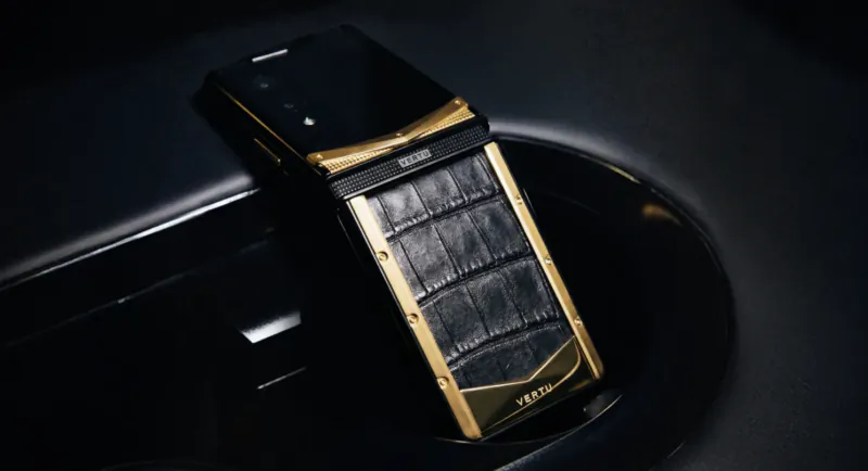 Luxury Vertu flip phone in black crocodile leather and gold, folded on dark surface