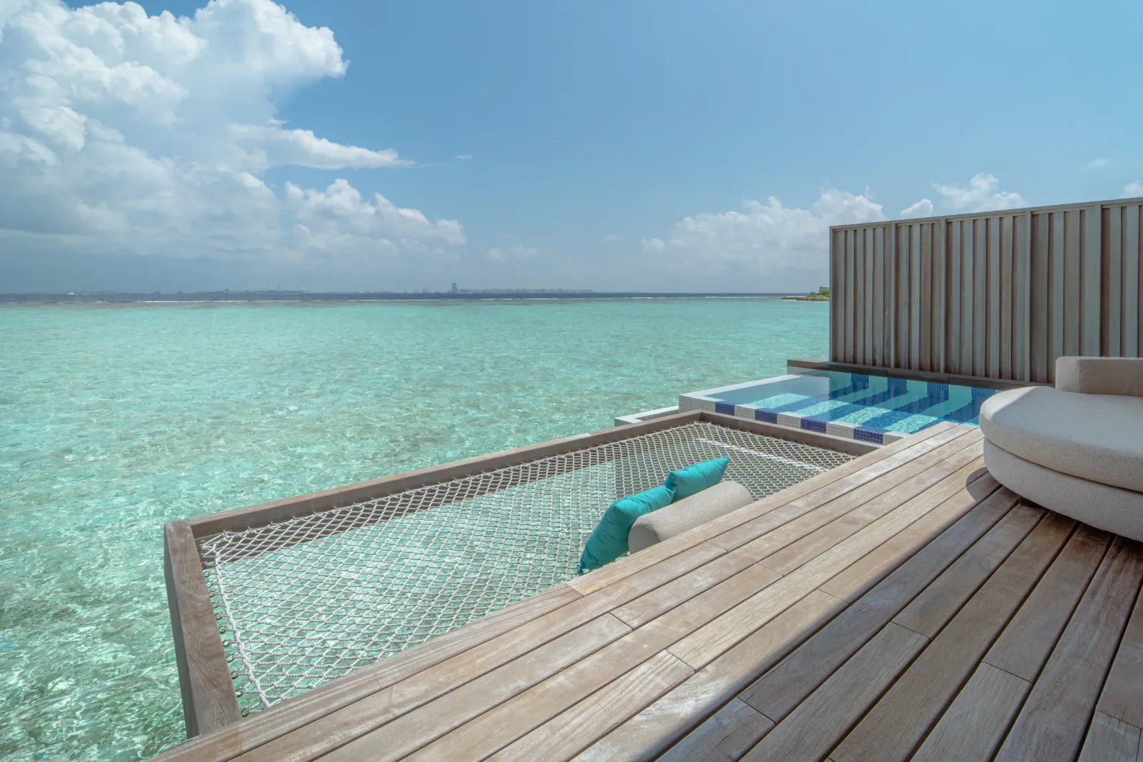 Overwater villa at SO/ Maldives with turquoise hammock, cushions, and ocean view under blue skies