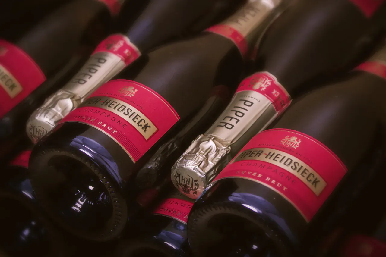 Close-up of Piper-Heidsieck champagne bottles with red labels in a rack, for World Champagne Day.