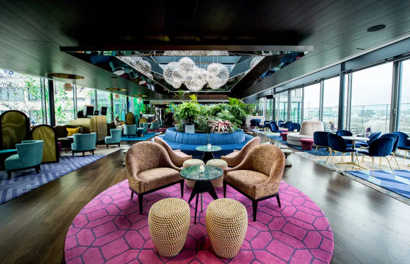 Sea Containers London spa aqua: Vibrant Winter Hedgerow gallery with colorful seating, plants, and city skyline view.