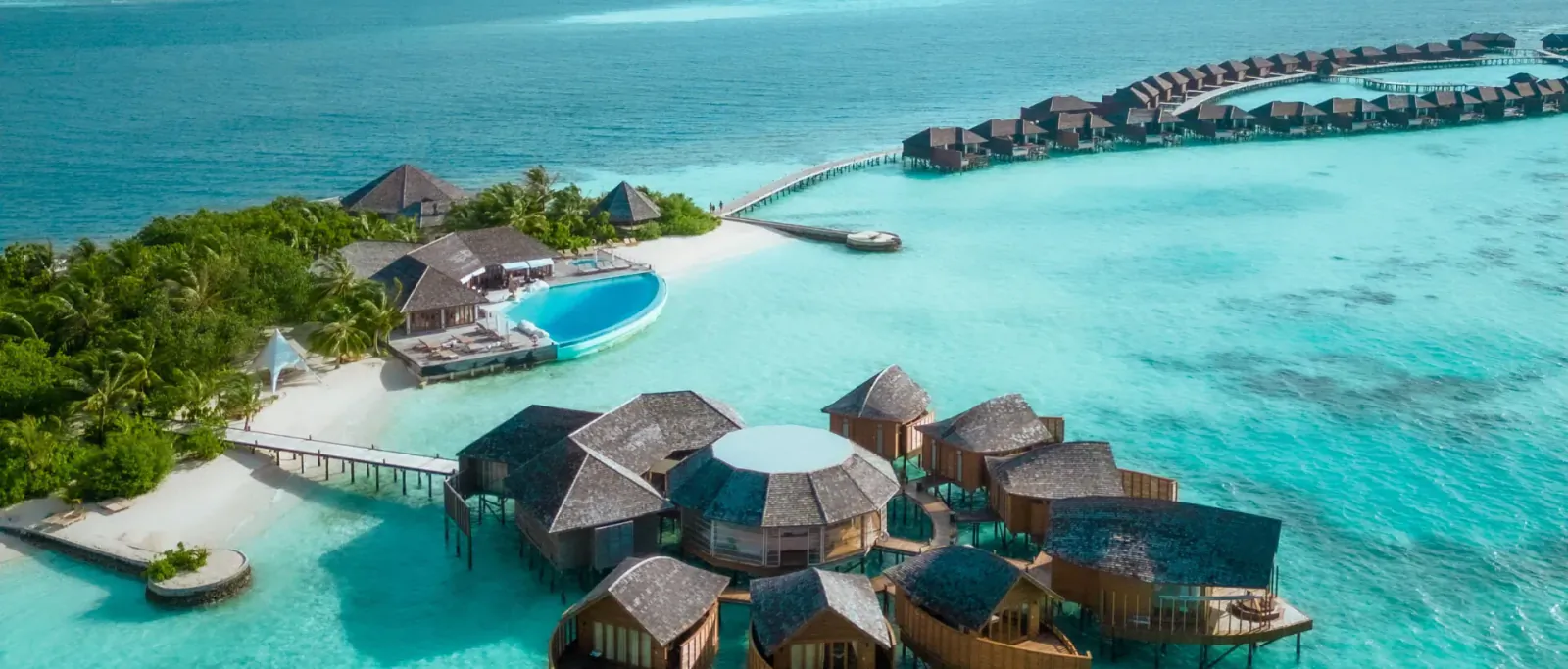 Aerial view of Lily Beach Resort's overwater villas, infinity pool, and turquoise lagoon in the Maldives