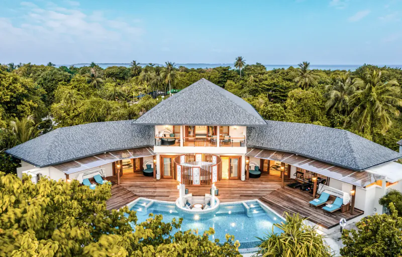 Aerial view of Hideaway Beach Resort's luxurious multi-level villa with infinity pool, wooden deck, and tropical surroundings.