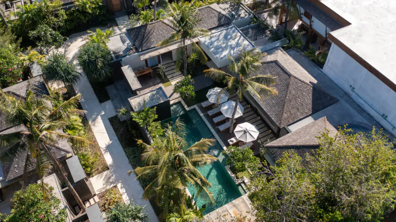 Aerial view of Cocana Resort in Gili Trawangan: luxurious villas, palm trees, and infinity pool with umbrellas.