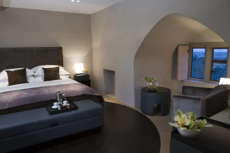 Luxurious bedroom in Roch Castle with arched walls, king bed, orchids, tray service, and window views.