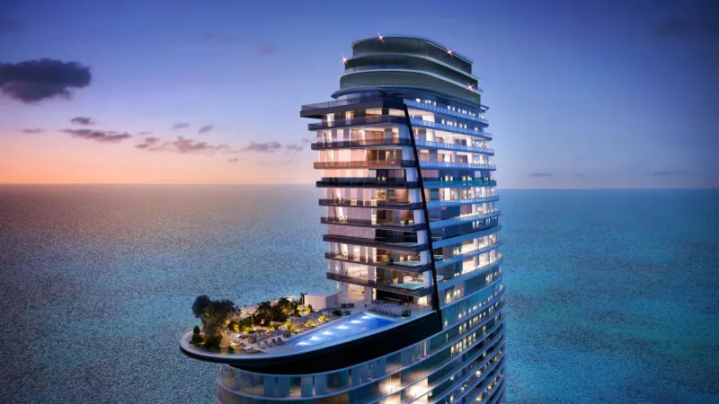 Aerial view of Aston Martin Residences luxury high-rise with rooftop pool and gardens at twilight over turquoise ocean