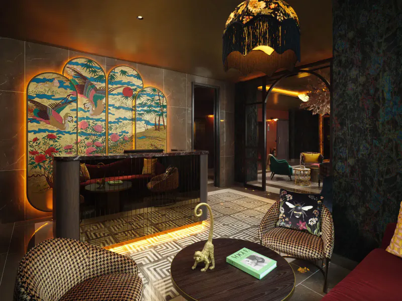 Elegant hotel lobby with gold monkey statue on table, bird screen, fringed lamp, and plush seating.