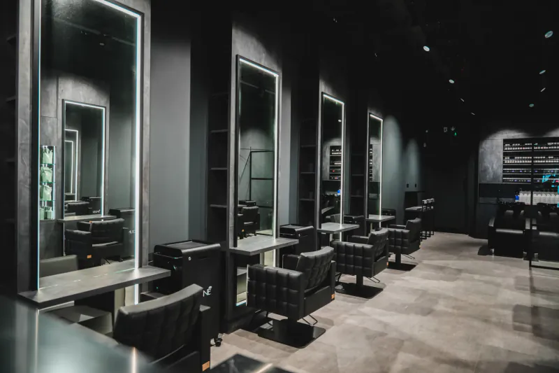 Modern black Luke Benson salon interior with LED-lit mirrors, black chairs, and styling stations.