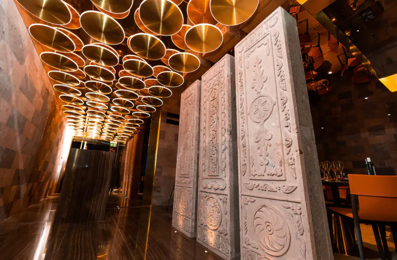 Elegant gallery hallway at Lusin Mayfair with ornate stone panels and glowing circular ceiling lights.