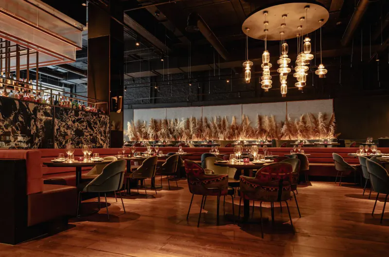 Elegant Gaucho restaurant interior in Cardiff with red velvet booths, patterned walls, pendant lights, and wooden floors.