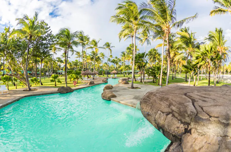 Aerial view of turquoise infinity pool with rock features and palm trees at Palm Island Resort & Spa, St Vincent.