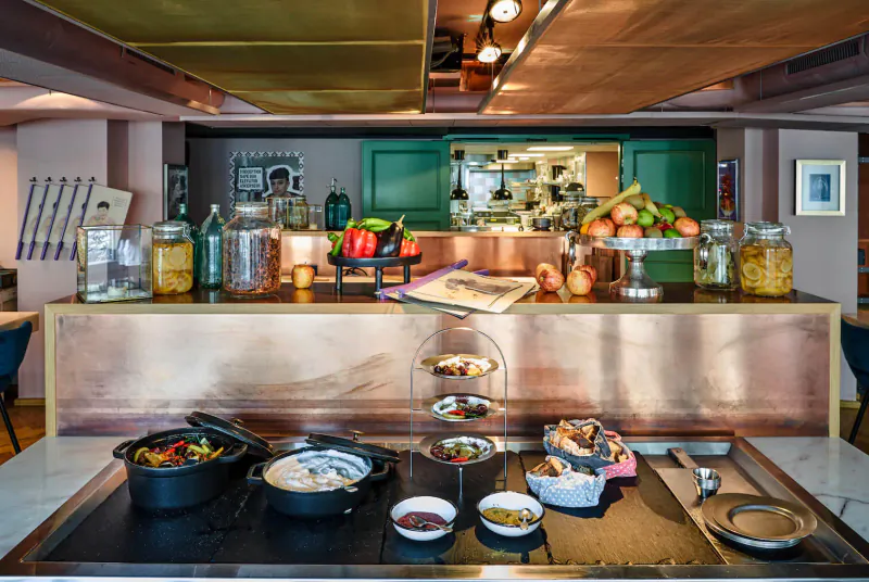Hotel buffet counter with brass accents displaying fresh fruits, vegetables, salads, pastries in sustainable Paris setting
