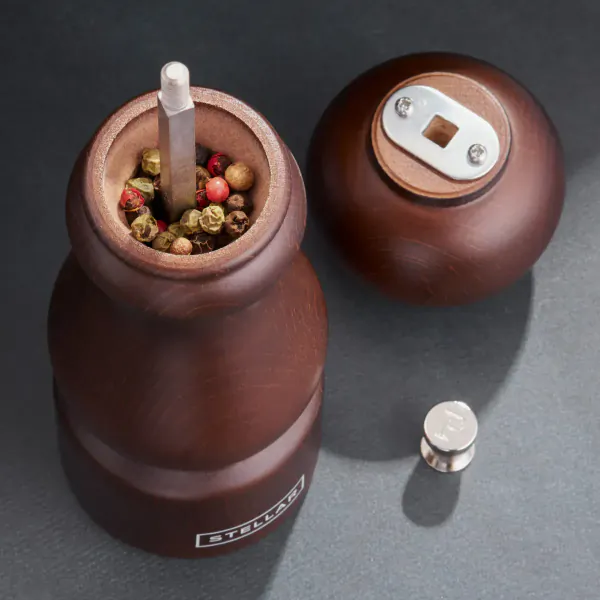 Open wooden Stellar Mills pepper grinder with grinder rod, multicolored peppercorns, closed mill, and metal adjustment nut