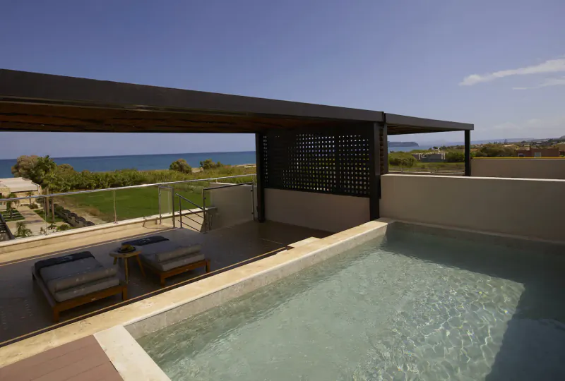 Infinity pool on Asterion Suites & Spa rooftop terrace in Crete, with sun loungers, sea view, and pergola.