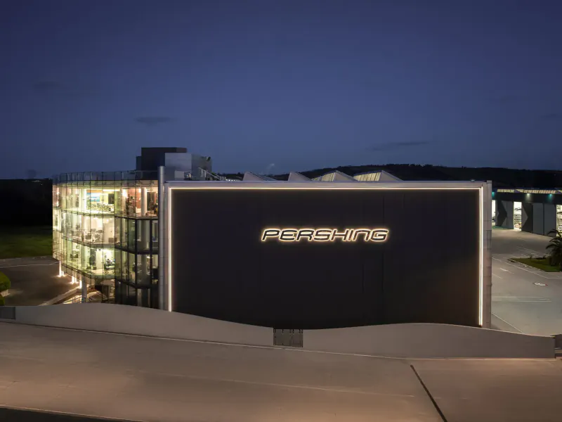 Modern Pershing building with 'PERSHING' sign illuminated at dusk, yacht gallery exterior.
