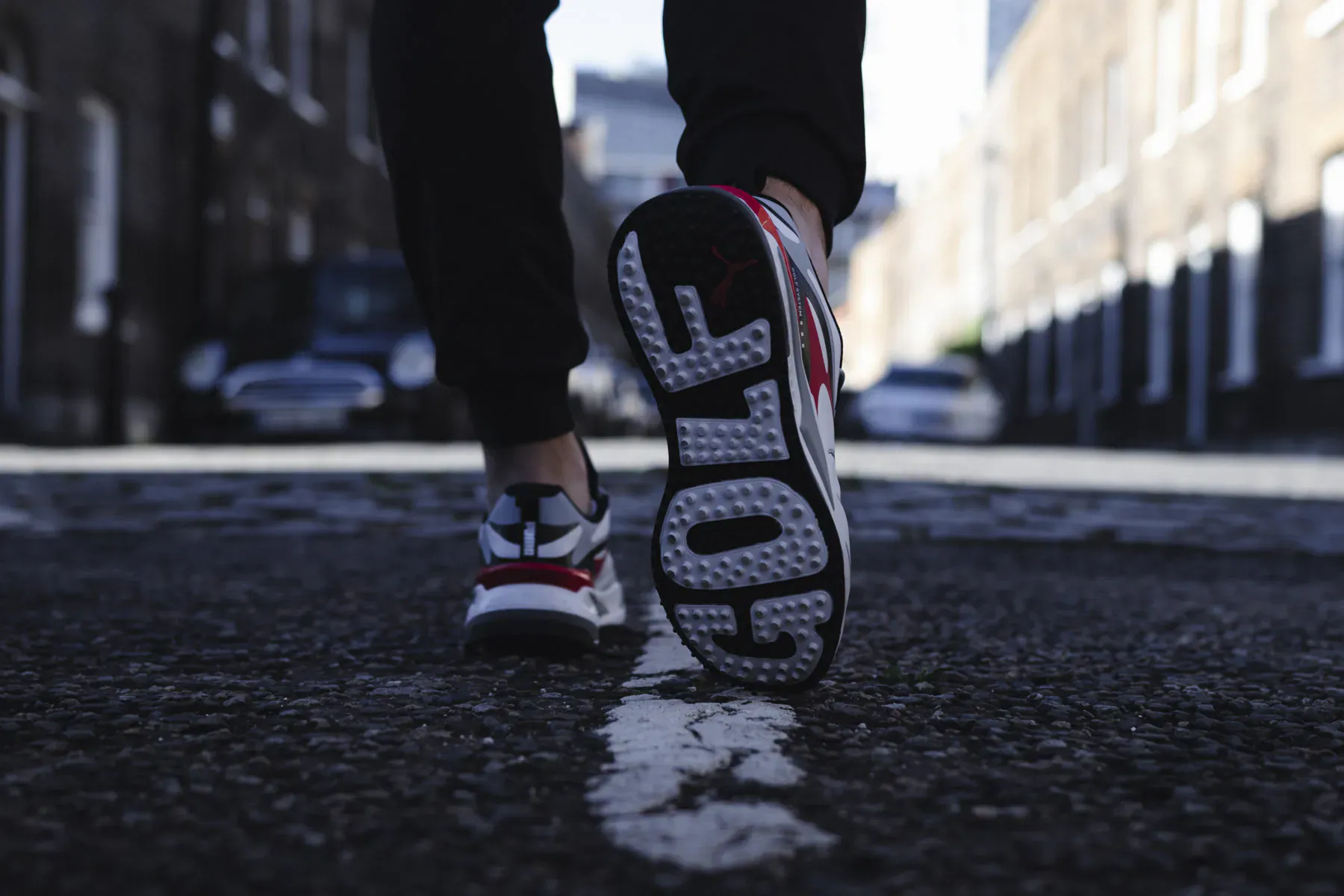 Close-up of white Golf sneakers with 'GOLF' on soles, walking on urban street, Valentine's gift idea.