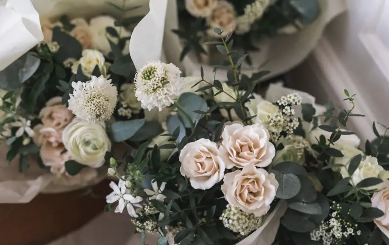 Close-up of elegant bouquet with white and pink roses, eucalyptus, and baby's breath wrapped in white paper