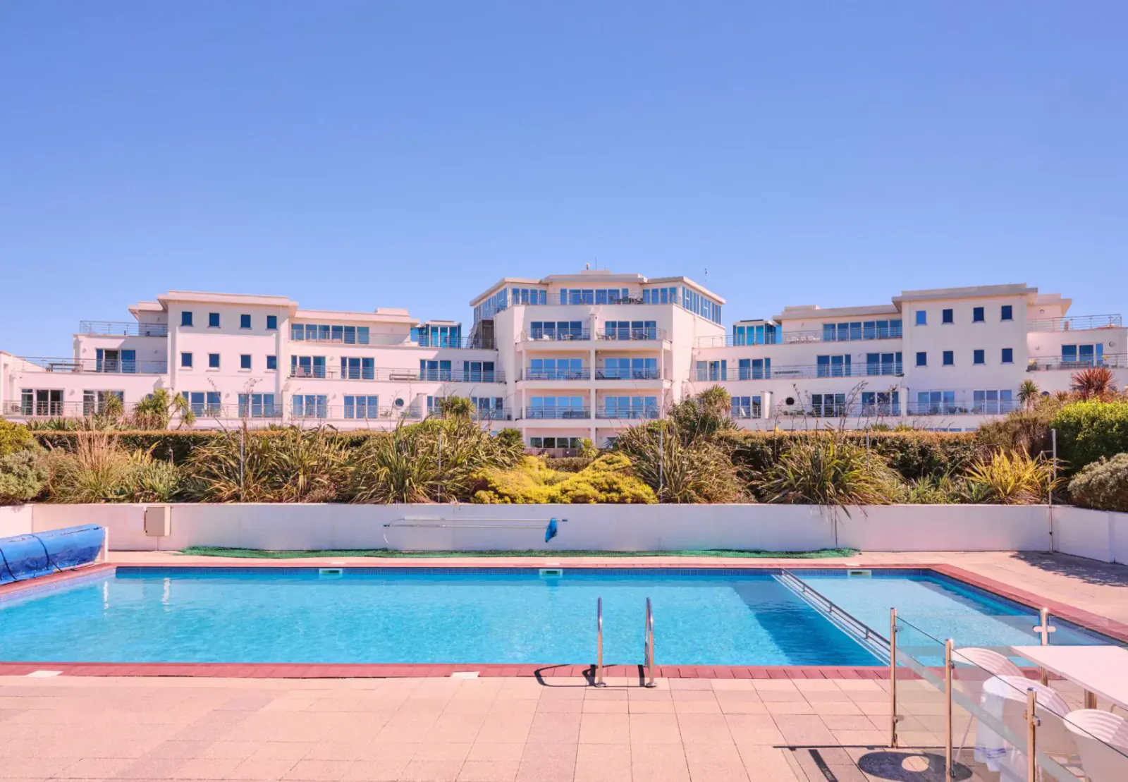 St Moritz Hotel in Cornwall: luxury white building with blue outdoor pool, gardens, and sunny sky