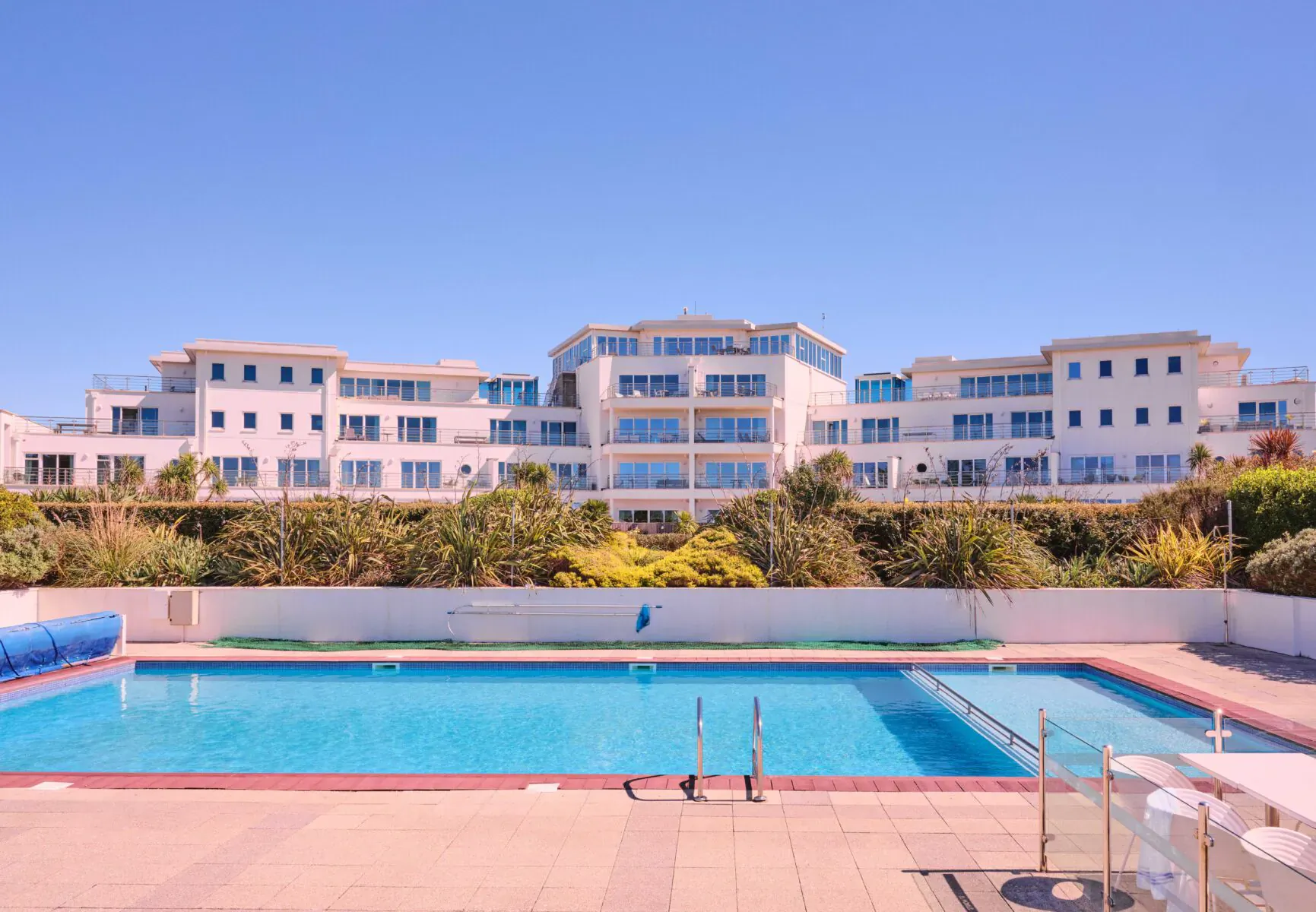 St Moritz Hotel in Cornwall: luxury white building with blue outdoor pool, gardens, and sunny sky