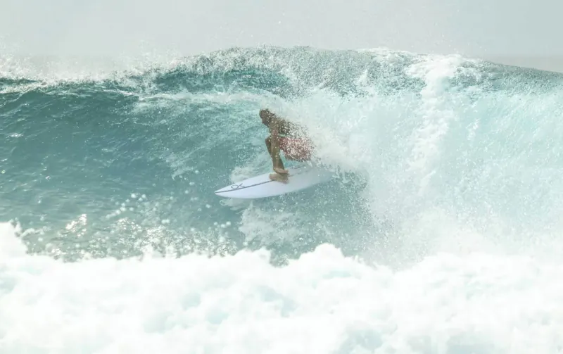 Surfer riding a large curling wave on white surfboard in the Maldives