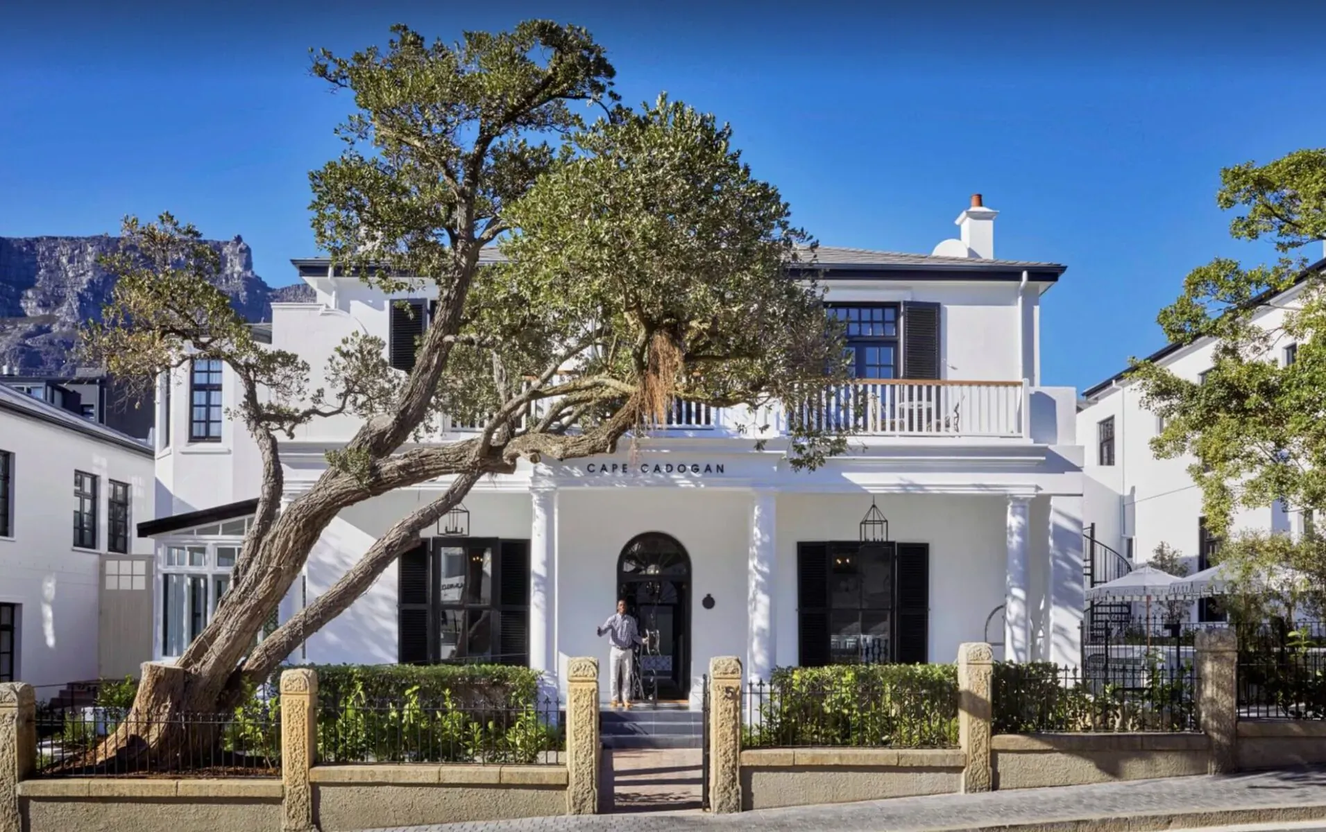 Cape Cadogan Boutique Hotel: white colonial-style building with large oak tree, balcony, and garden in Cape Town.