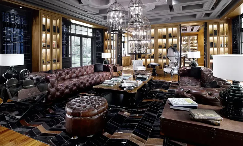 Luxurious hotel lounge with tufted leather sofas, chandeliers, wooden cabinets, and coffee tables on patterned rug.