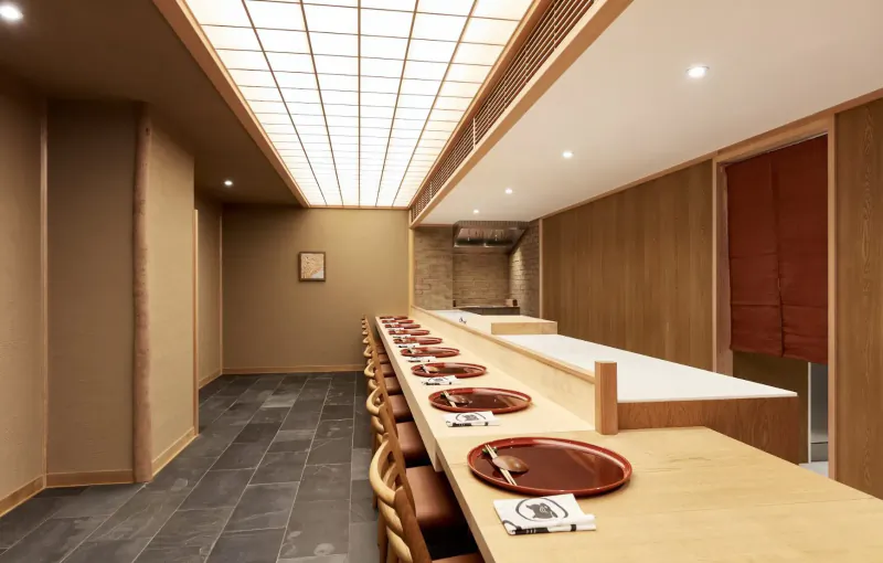 Elegant Japanese kaiseki sushi bar counter with wooden stools, red plates, chopsticks, under glowing shoji ceiling.