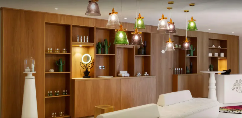 Marcel Wanders-designed hotel lobby with wooden cabinets, colorful pendant lights, plants, and white seating.