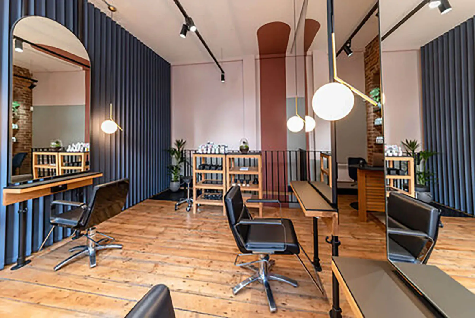Modern Bond Shoreditch hair salon interior with black stylist chairs, wooden stations, mirrors, plants, and warm lighting.