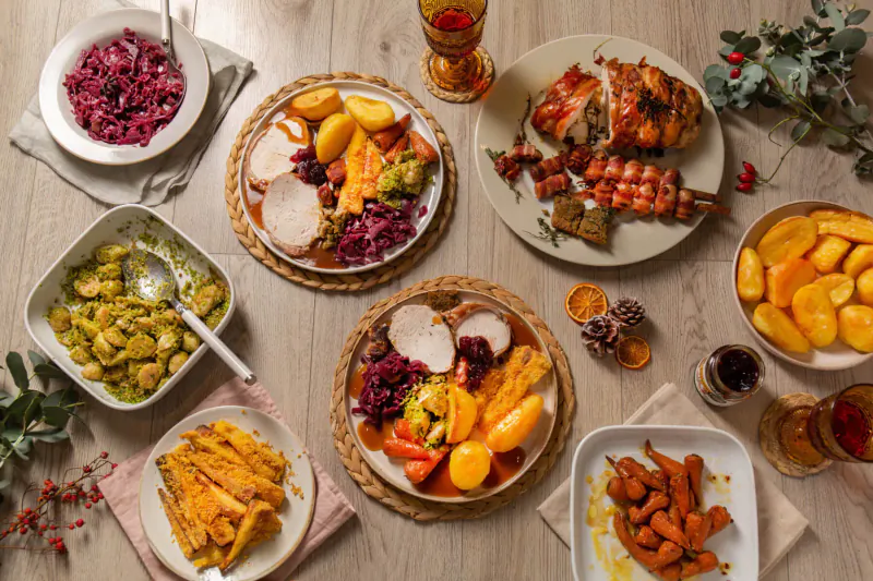 Christmas dinner box with roast turkey, beets, potatoes, green beans, carrots on wooden table with festive decor.