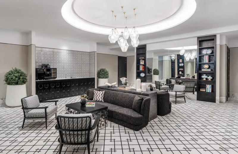 Modern hotel lounge at Fairmont La Marina Rabat-Salé with gray sofa, chairs, bookshelves, plants, and pendant lights.