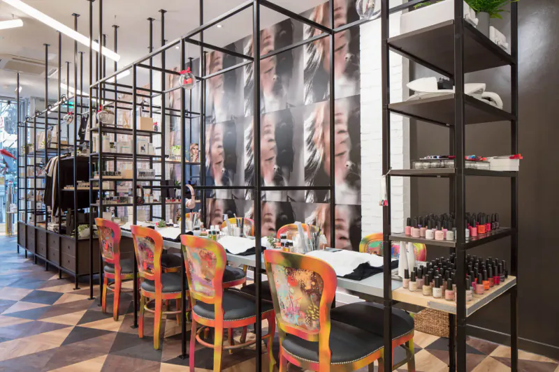 Modern nail salon station at Young LDN Medispa with colorful patterned chairs, polish racks, and Andy Warhol-style wall murals.