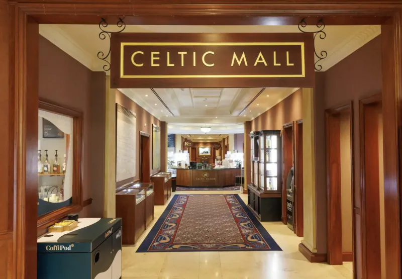 Elegant entrance to Celtic Mall at Celtic Manor Resort, with wooden archway, red carpet, and display cases.