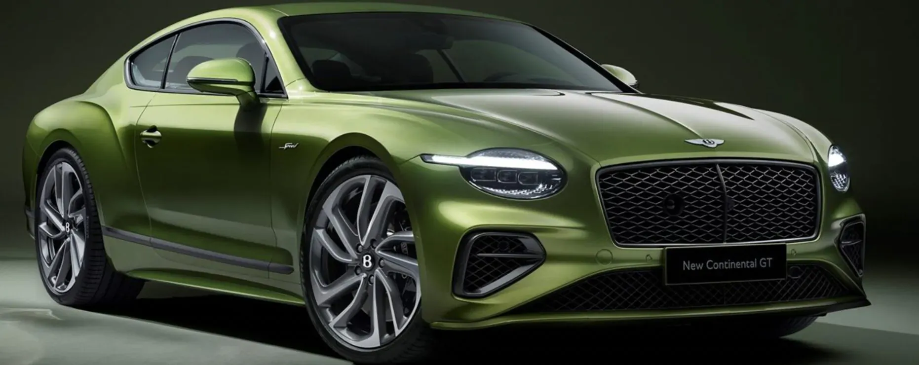 Emerald green Bentley Continental GT coupe, front view, with 'New Continental GT' badge, on dark studio background.