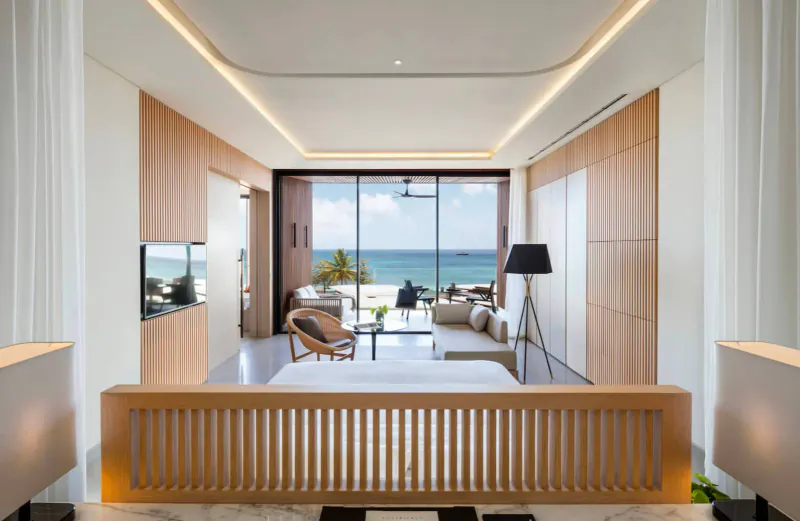 Spacious Silversands Grenada suite with wooden walls, king bed, lounge seating, and ocean view balcony.