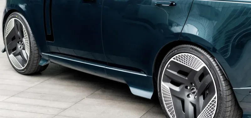 Side view of Racing Green luxury sports car with distinctive black alloy wheels on pavement