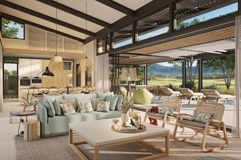 Spacious modern Mauritian villa living room with teal sofa, rattan chairs, open kitchen, pool, and mountain views.