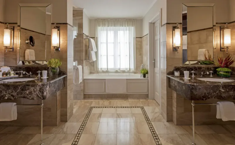 Elegant symmetric bathroom at Four Seasons Hotel The Westcliff, Johannesburg, with marble vanities, freestanding tub, and window view.