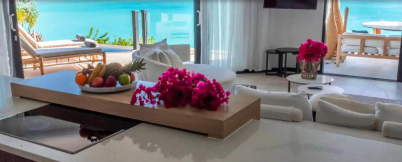 Luxury kitchen counter with tropical fruits, pink hibiscus, and sea view balcony at Tamarind Hills Antigua