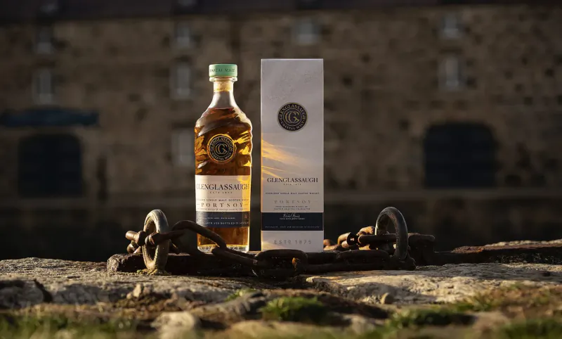 Luxuria No 7 whisky bottle and white box on iron chains atop stone wall before castle, Valentine's luxury gift.