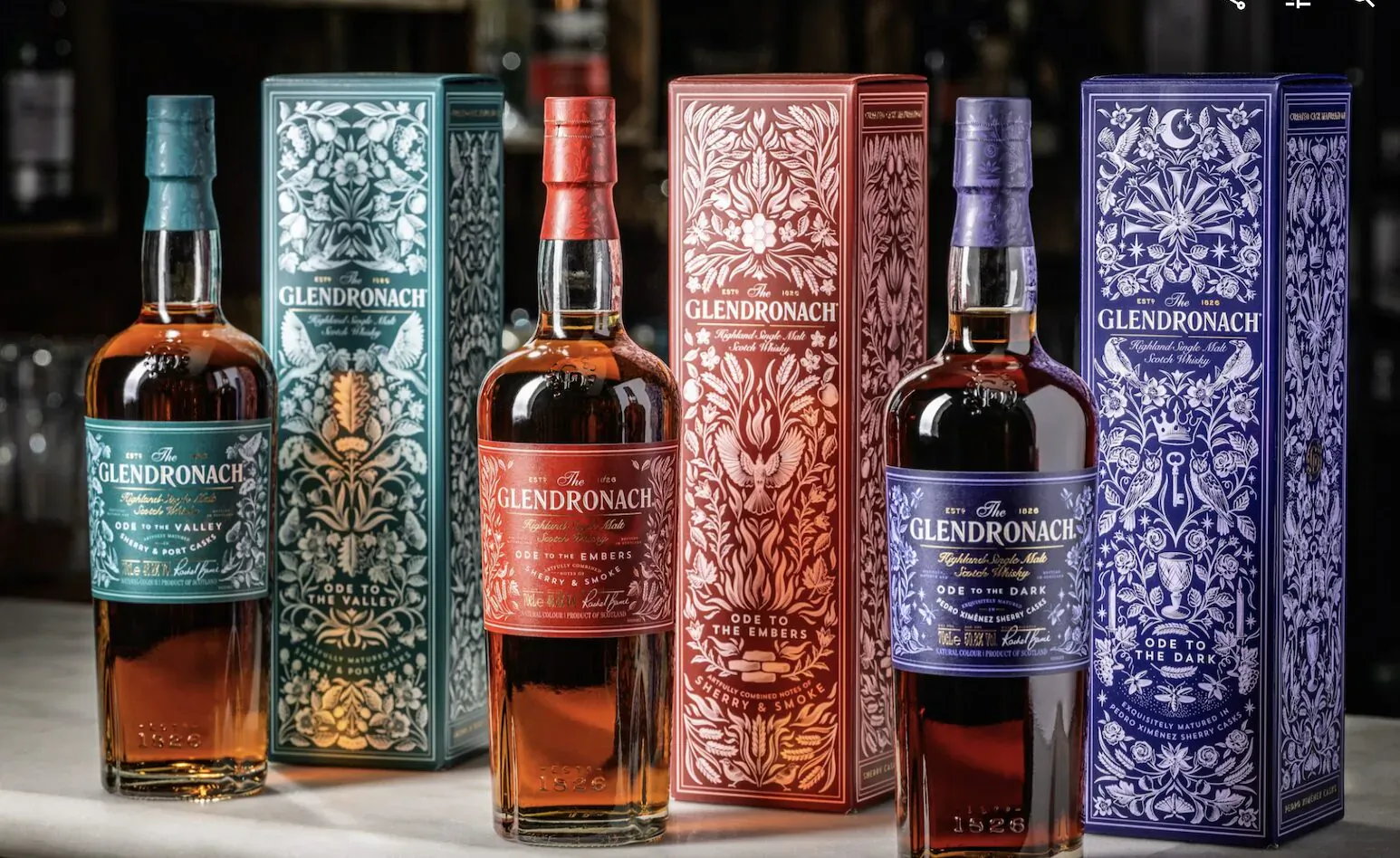 Glendronach Master's Anthology: three whisky bottles in green, red, and blue ornate boxes on a table.