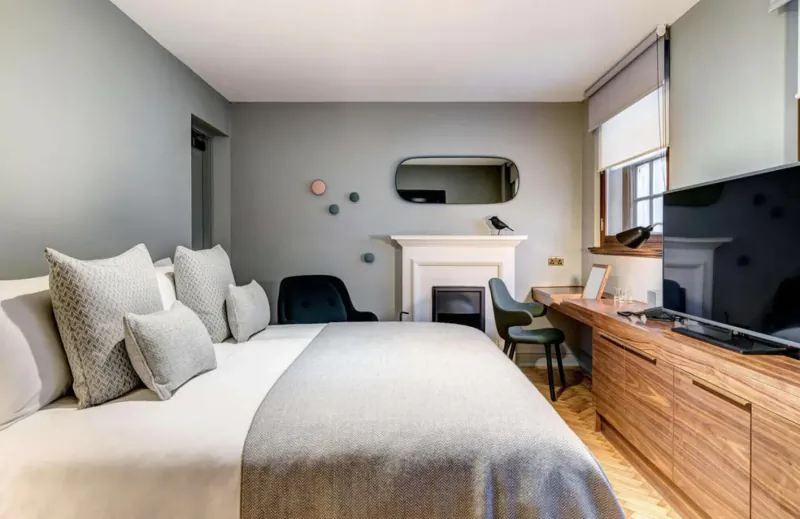 Cozy Apex Temple Court hotel room in London with king bed, fireplace, desk, and window.