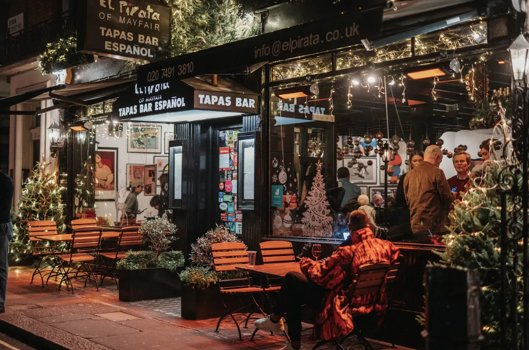 El Pirata Spanish Tapas Bar in Mayfair at Christmas, with outdoor seating, patrons, and festive lights and trees.