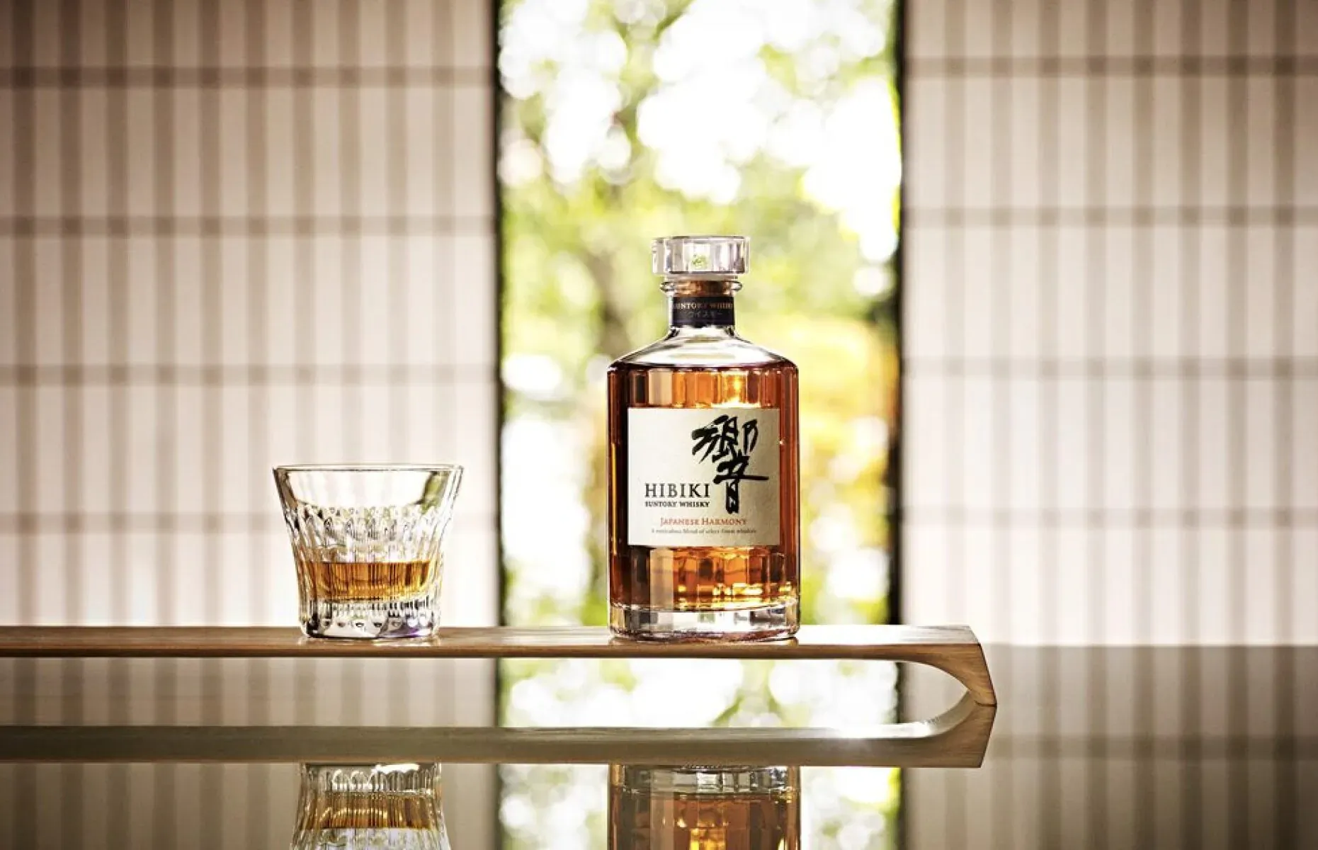 Hakuroku Japanese whisky bottle and glass of amber liquid on wooden tray by shoji window with garden view