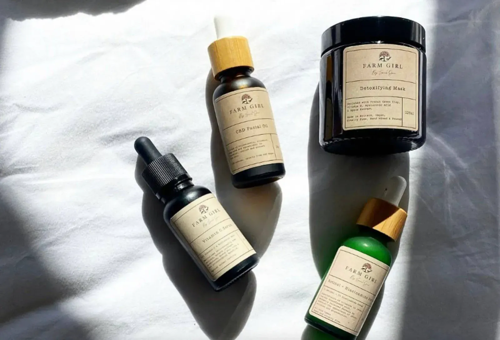Farm Girl skincare products on white surface: Retinol & Niacinamide Serums in dropper bottles, Cleansing Balm jar, natural light.